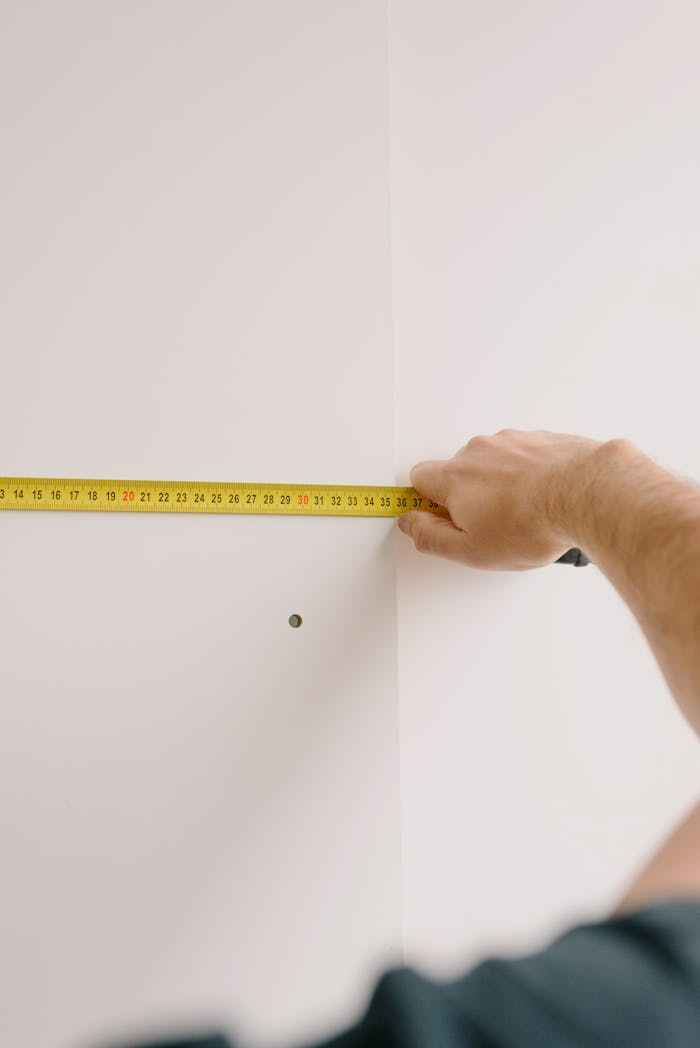 Crop man measuring wall at home